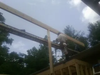 Carpenter setting a ridge beam over a new addition frame — Ice Dam Removal by Roofing Brothers in Piketon