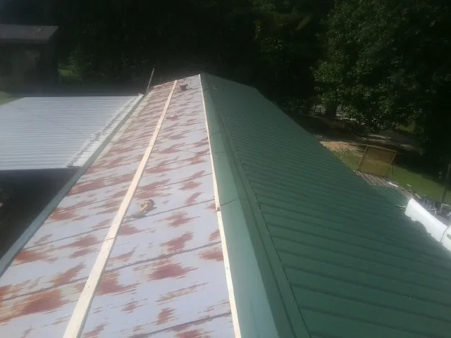 Old rusted panels beside newly installed green metal roofing — Wind Damage Roof Repair by Roofing Brothers in Piketon