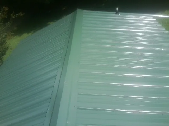 New green metal panels meeting at the ridge of a roof — Flat Roof Repair work by our crew in Piketon