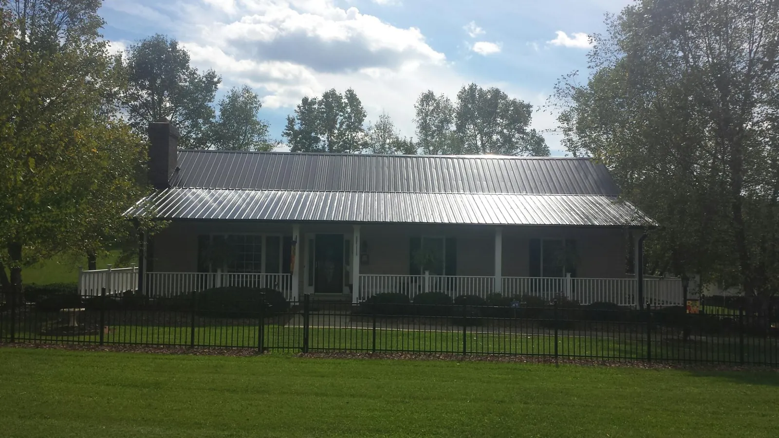 Gray metal roof on a brick ranch with a full width front porch — Gutter Guard Installation work by our crew in Piketon
