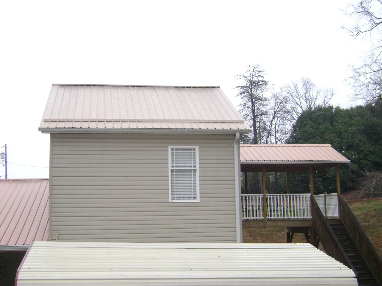 Tan metal roofs on a two story addition and attached porch, from a Roof Replacement job in Piketon